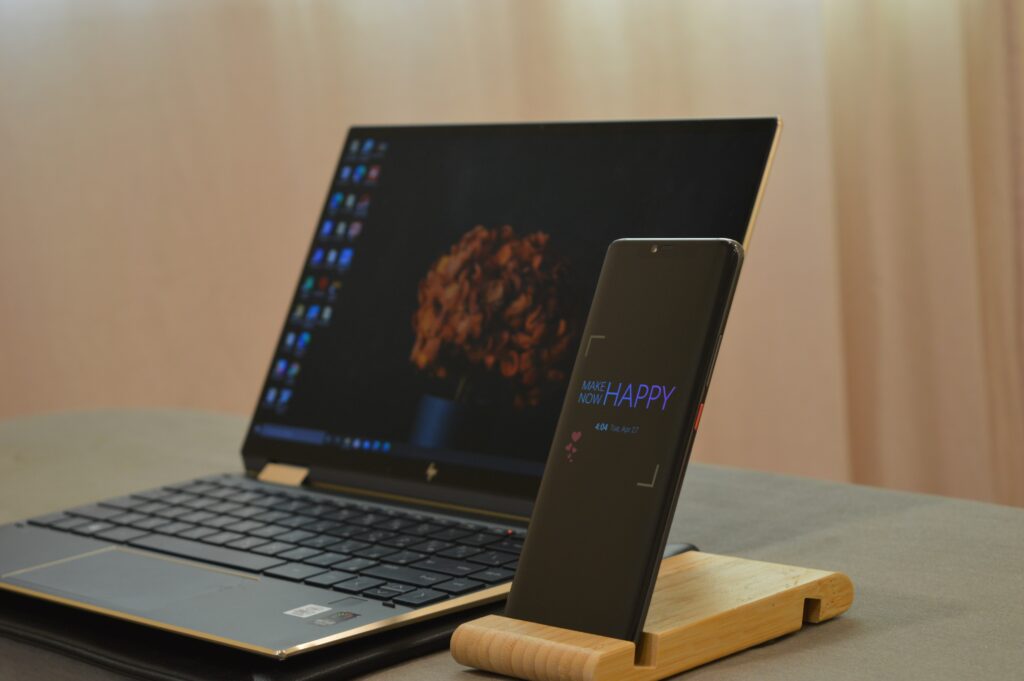 HP Spectre x360 laptop with open display and with mobile in the wooden desk.