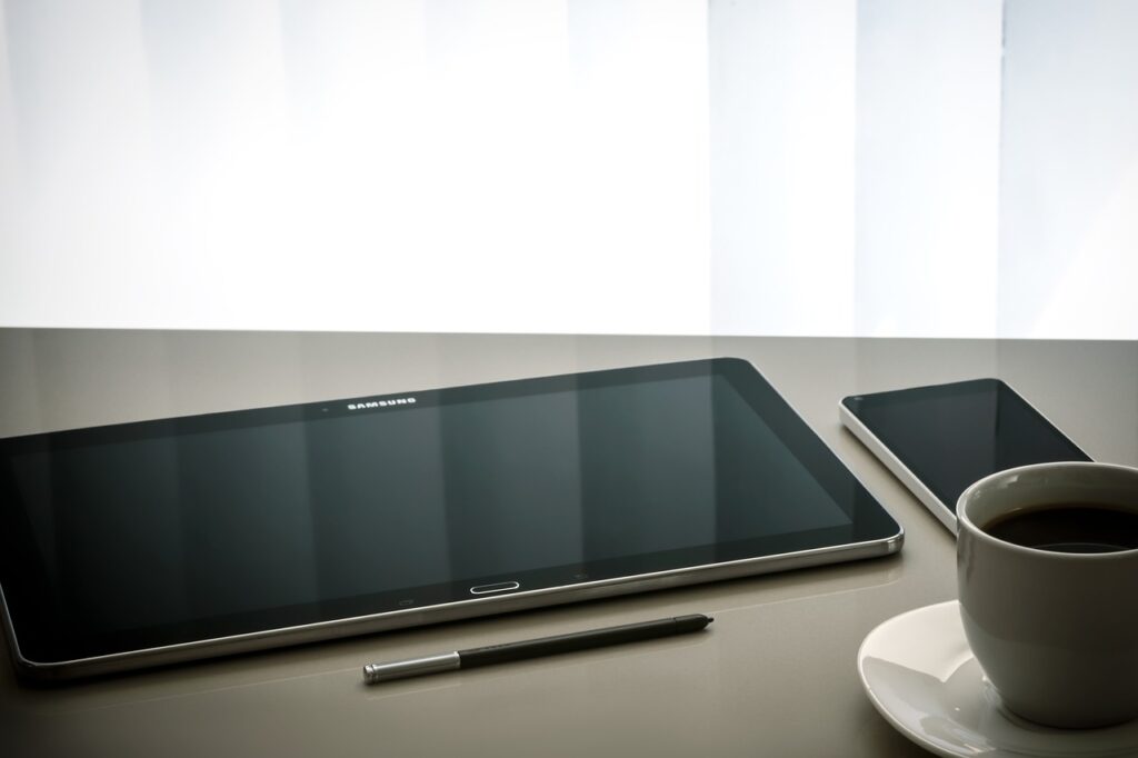This image shows the Samsung Galaxy Book 2 pro 360 with it's pen mobile and a cup of coffee in the table.